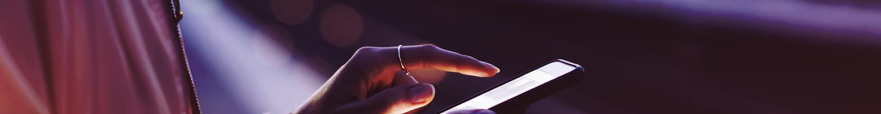 Hand using mobile phone on train platform.