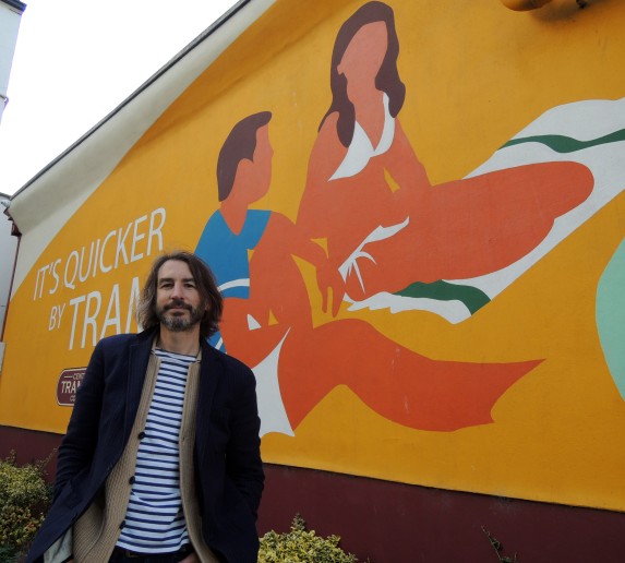 Image of Adrian Riley with a mural he created.