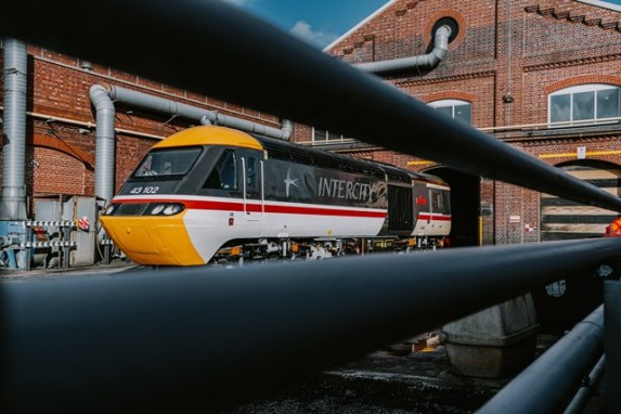 Image showing HST 43102 in original livery, freshly painted and departing the depot building, viewed at a distance.