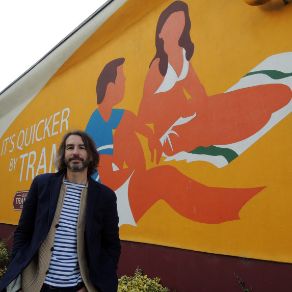 Image of Adrian Riley with a mural he created.